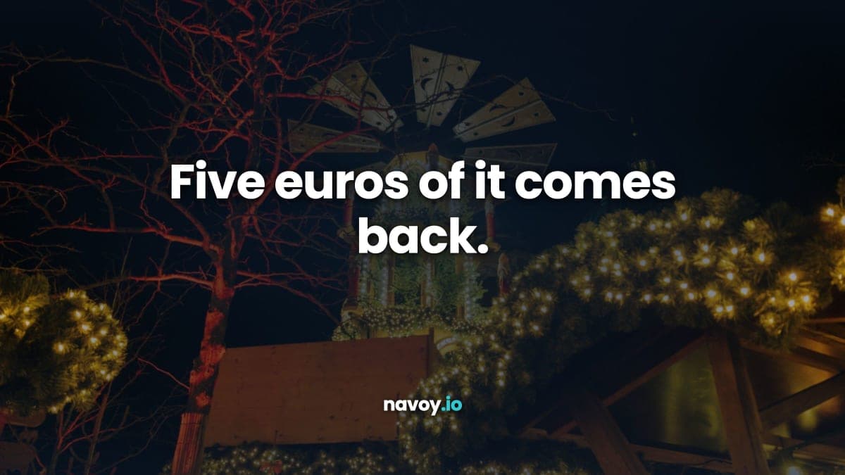 A lit German Christmas pyramid turning above market stalls at night, fir garlands strung with warm lights below