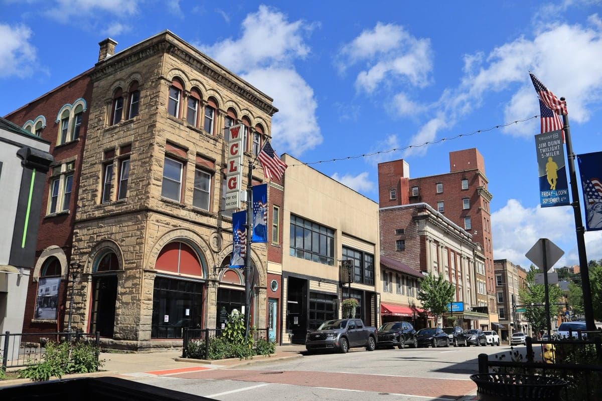 Historic commercial buildings along High Street in downtown Morgantown, West Virginia, under a blue sky