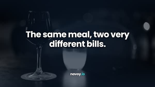 A glass of red wine and a candle on a dark restaurant table, photographed in black and white